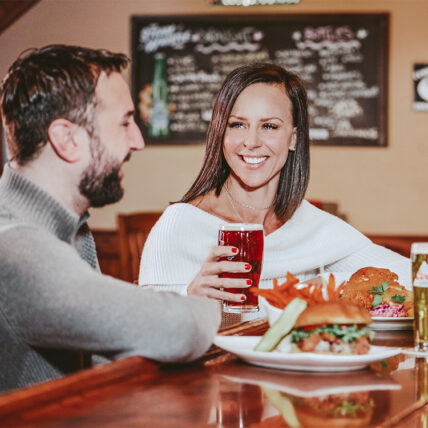 A couple enjoying comfort foods from Jordan House Tavern, minutes from Inn On The Twenty